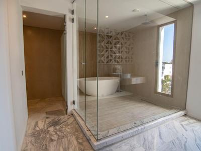 Baño moderno con bañera independiente, ducha de vidrio y ventana grande con vista a la ciudad.