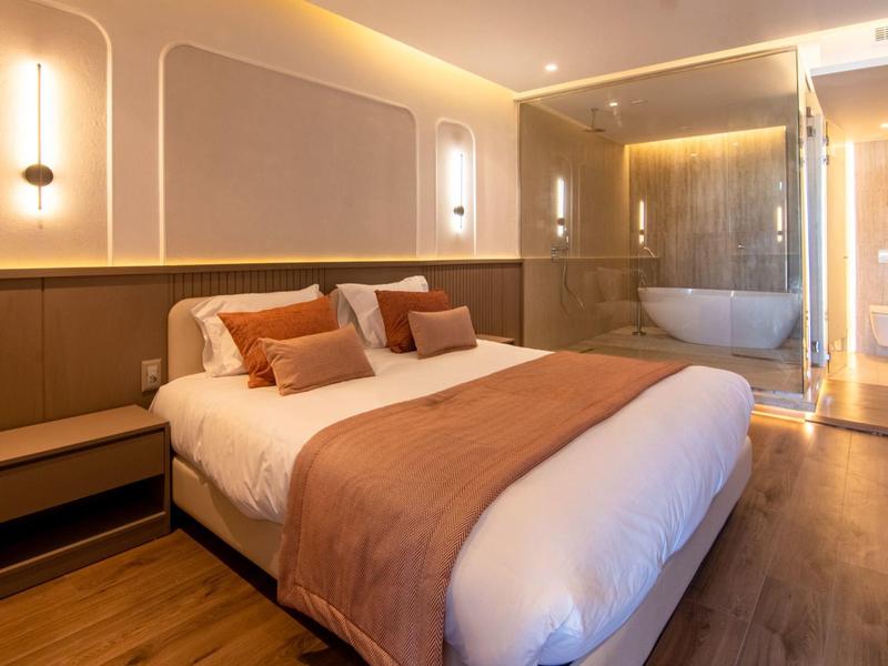 Habitación de hotel moderna con cama doble y baño contiguo con bañera.