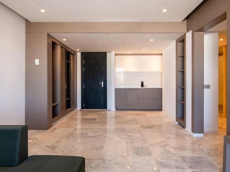 Habitación de hotel moderna con suelo de mármol, paneles de madera y luz indirecta sutil.