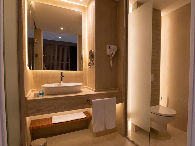 Baño moderno con lavabo, toallas y un inodoro bajo una luz cálida.