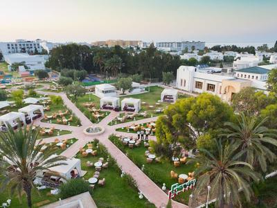 Luxuriöse Hotelanlage mit Gärten, Pools und Pavillons nahe dem Meer unter klarem Himmel.