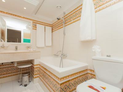 Badezimmer mit Badewanne, Toilette, Waschbecken und dekorativen Fliesen.