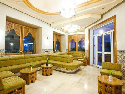 Helle Lounge mit grünen Sitzmöbeln und hölzernen Tischen in einem eleganten Hotelinterieur.