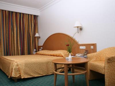 Ein gemütliches Hotelzimmer mit Doppelbett, Sitzgruppe und Tisch mit Blume.