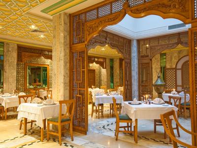 Elegantes Restaurant mit weißen Tischdecken und kunstvollen Holztrennwänden in einem luxuriösen Hotel.