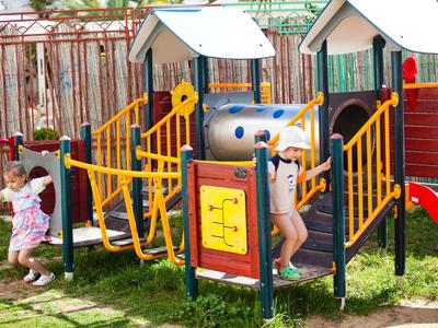Kinder spielen auf einem bunten Spielplatz mit Rutschen und Kletternetzen im Freien.