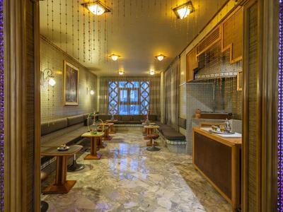 Blick in eine elegant eingerichtete Hotellounge mit Sitzbänken, Tischen und gemusterten Wänden.