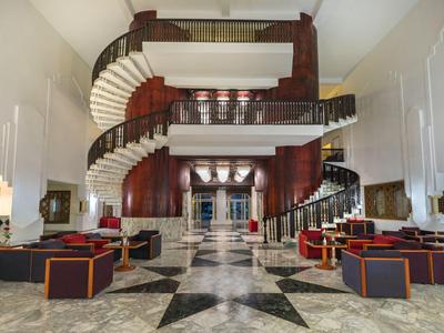 Großer Hotel-Lobby mit zwei spiralförmigen Treppen und moderner Sitzgruppe