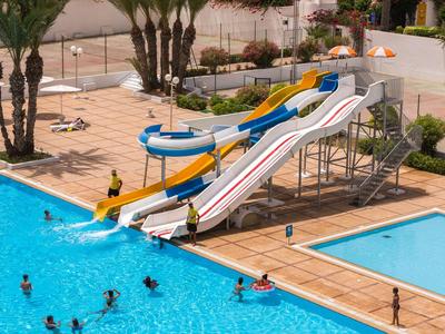 Großer Poolbereich mit Wasserrutschen und Menschen beim Schwimmen.