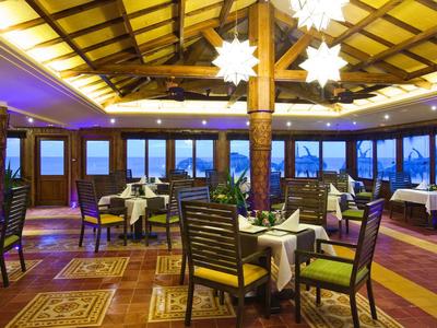 Elegantes Hotelrestaurant mit Holzbalken und großen Fenstern mit Blick auf das Meer.