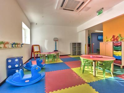 Bunter Kindergartenraum mit Schaumstoffboden, Spielzeug und kleinen Tischen und Stühlen aus Kunststoff.