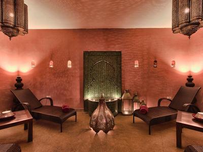 Gemütlicher Raum mit warmem Licht, zwei Liegestühlen, orientalischen Lampen und dekorativem Kamin.