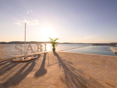 Weite Terrasse mit Pool, Sonnenschirm und Pflanze, Sonnenuntergang am ruhigen See im Hintergrund.