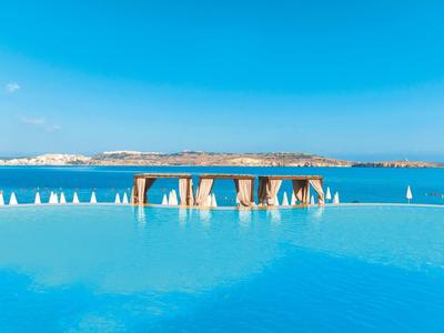 Infinity-Pool mit blauem Wasser, weißen Sonnenschirmen und weitem Blick auf das blaue Meer.