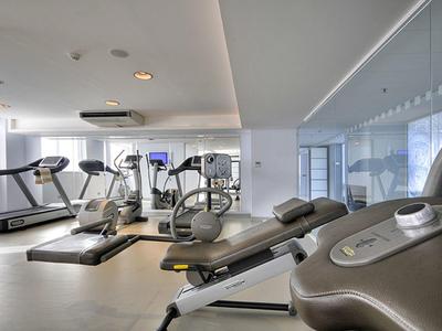 Moderne Fitnessstudio mit Laufbändern, Crosstrainern und Hantelbänken in hellem Raum.