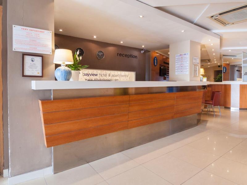 Moderner, heller Empfangsbereich mit langem Holztresen und cremefarbenen Wänden.