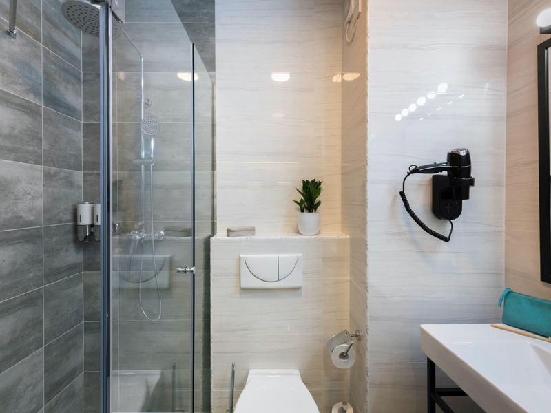 Moderner Badbereich mit Glas-Dusche, Wand-WC, Haartrockner und Waschbecken mit Spiegel.