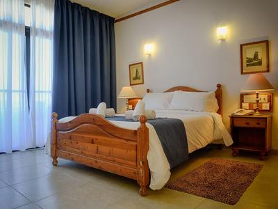 Gezellige hotelkamer met houten bed, nachtkastje, vloerkleed, gordijnen, natuurlijk licht.