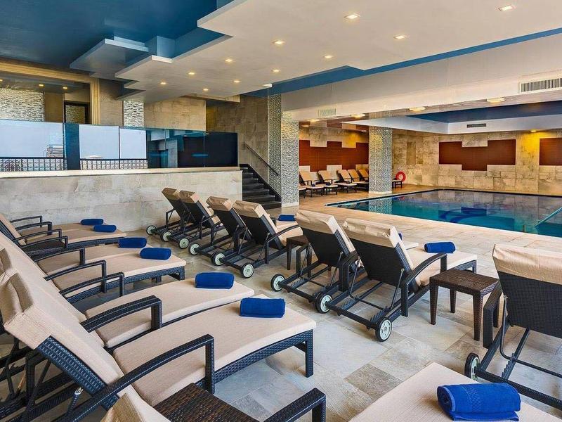 Moderne binnenzwembad met ligstoelen en planten in een lichte, stijlvolle ruimte.