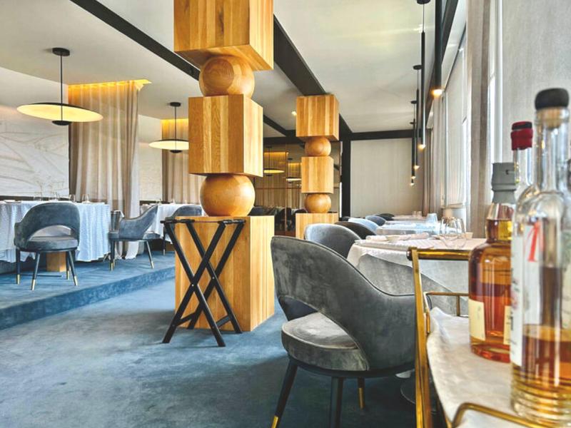Modern hotelrestaurant met grijze stoelen en houten kolommen in een elegante omgeving.
