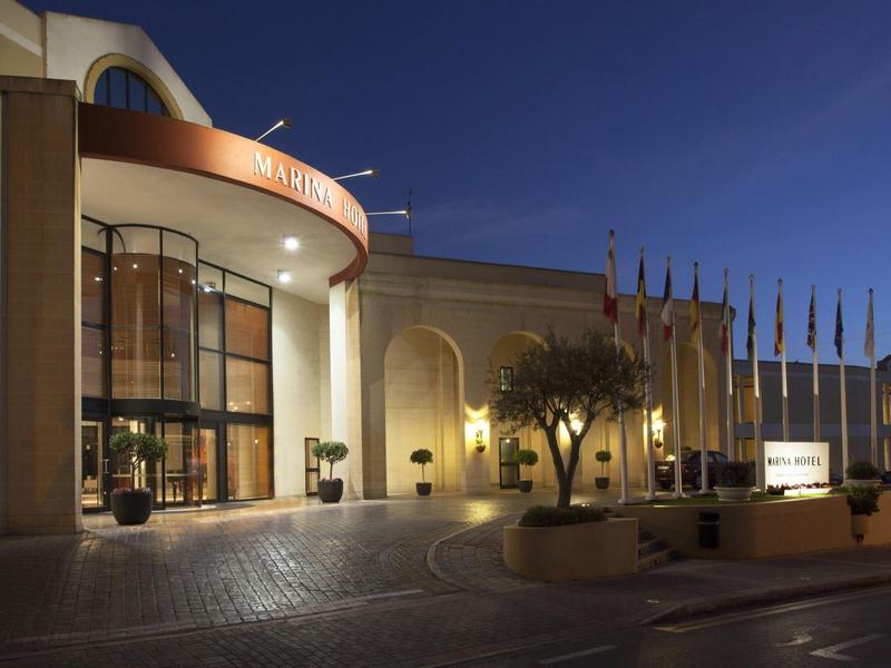 Modernes Gebäude mit großer Glasfassade und beleuchtetem Eingangsbereich bei Nacht.