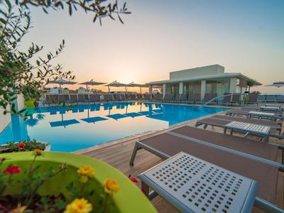 Moderner Swimmingpool mit Liegestühlen und Sonnenuntergang am Hotel