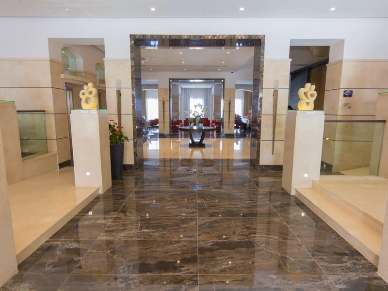 Luxurious hotel lobby with polished marble floor, elegant statues, and open passageways.