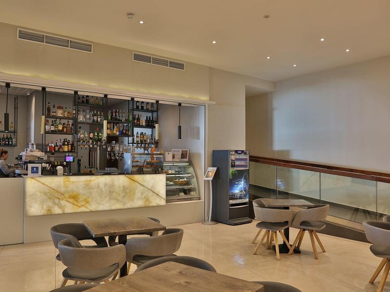 Moderne Hotellounge mit stilvoller Bar, bequemen Stühlen und Tischen in warmem Licht.