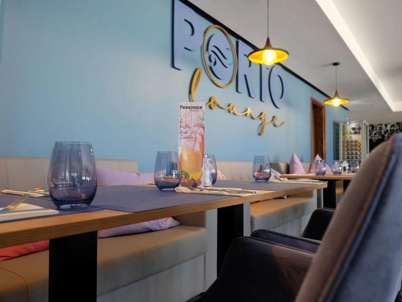 Moderner Hotelrestaurantbereich mit Tischen, komfortablen Stühlen und dekorativer Wandbeleuchtung.