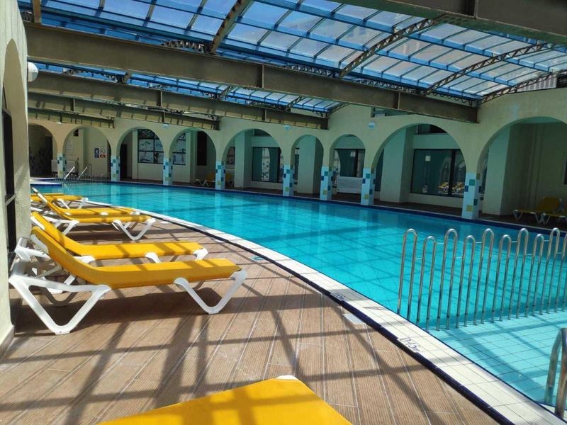 Innenpoolbereich mit gelben Liegestühlen und gläsernem Dach in einem Hotel.