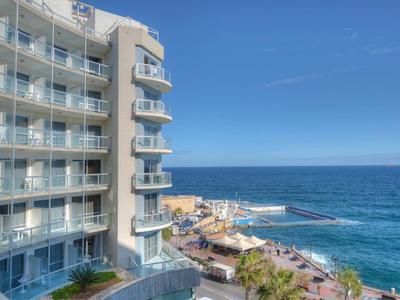 Moderner Hotelkomplex mit Balkonen neben dem Meer unter klarem blauem Himmel.