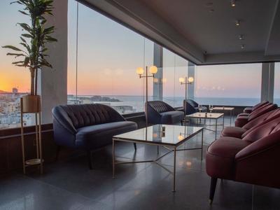 Moderne Hotellounge mit Sofas und Panoramafenstern bei Sonnenuntergang.