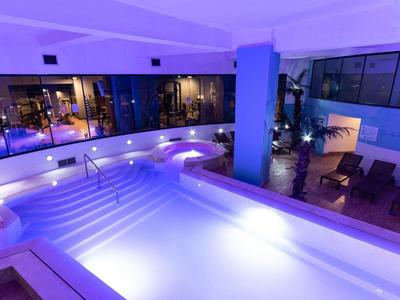 Moderner Indoor-Pool in einem Hotel mit blauer Beleuchtung und Liegestühlen.