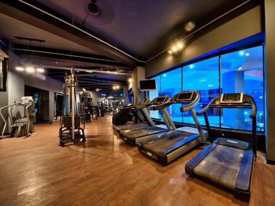 Moderne Hotel-Fitnessraum mit Laufbändern und Ausblick auf blaue Fenster.