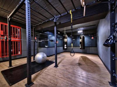 Moderner Fitnessraum mit Holzfußboden, Hantelständer, Gymnastikball und Boxsäcken.