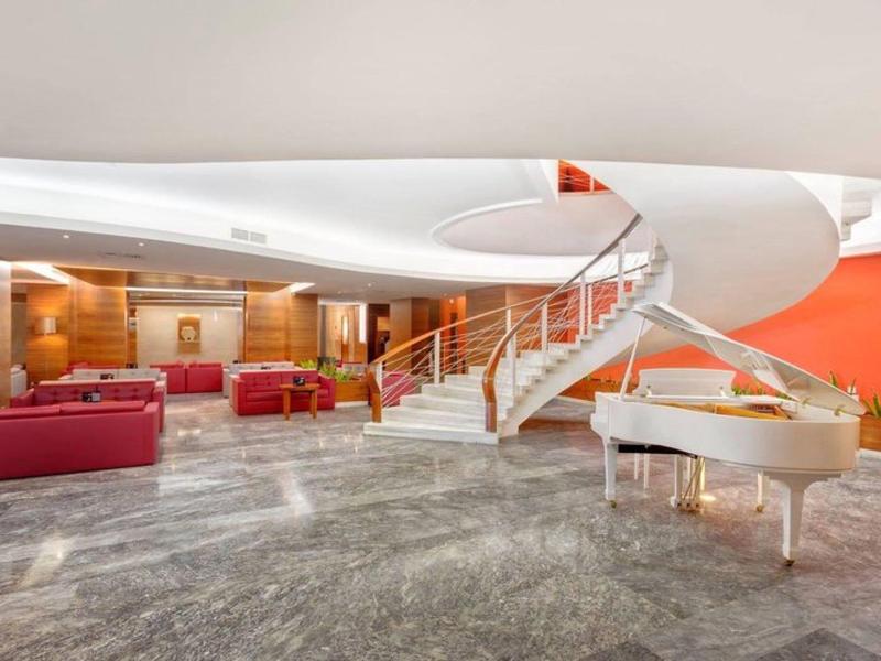 Modernes Hotelzimmer mit weißen, geschwungenen Treppen und einem weißen Flügel in einem geräumigen Bereich.