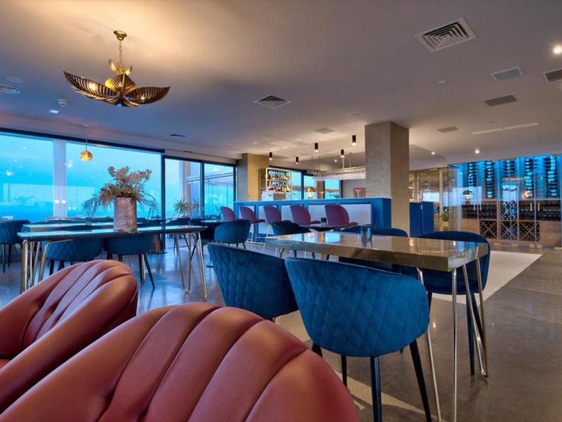 Modernes Hotelrestaurant mit stilvollen Sitzgelegenheiten und großen Fenstern mit Meerblick.