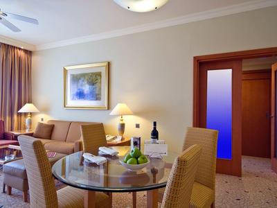 Habitación de hotel luminosa con sofá, mesa, sillas y iluminación moderna