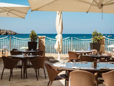 Terrazza con tavoli e sedie sotto ombrelloni con vista sul mare.