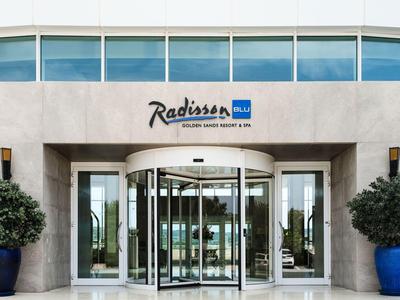 Eingang des Radisson Blu Hotels mit Drehkreistür und zwei großen blauen Pflanzgefäßen.