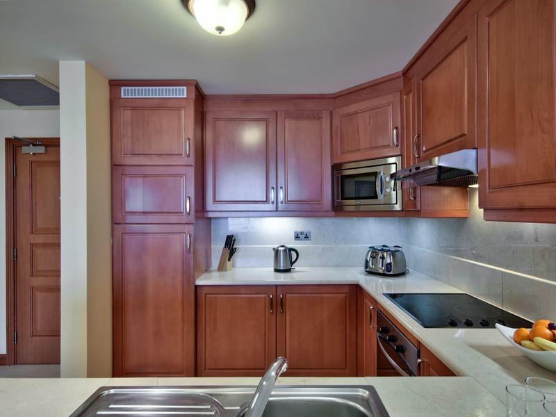 Cocina moderna con muebles de madera, microondas, tostadora, hervidor y estufa en apartamento vacacional.