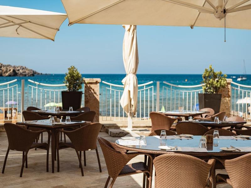 Terraza con mesas y sillas preparadas con vista al mar en un día soleado