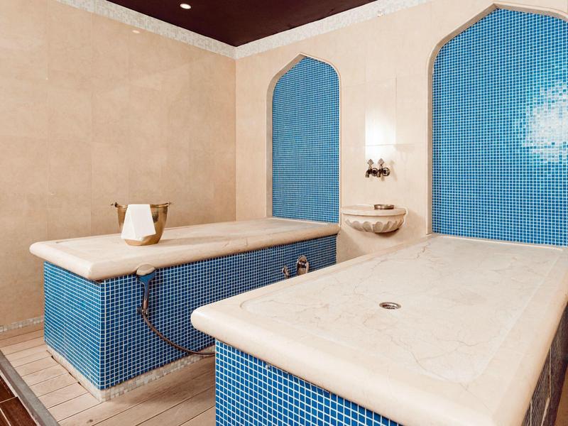 Sala de spa moderna con dos camillas de mármol azul y paredes neutras.