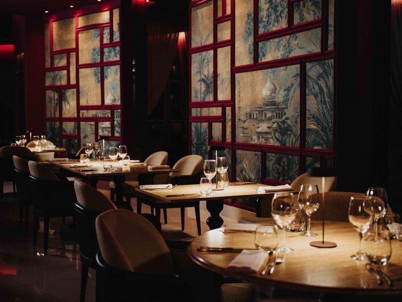 Elegante interior de restaurante con mesas preparadas y luz cálida roja.