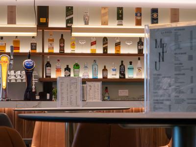 Moderne Bar mit beleuchteten Regalen und Getränkekarten auf Tischen.