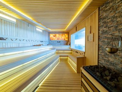 Moderner Wellnessbereich mit Sauna aus Holz und beleuchteten Sitzstufen in warmem Licht