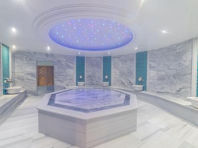 Moderner türkischer Dampfbadraum mit Marmorwänden und beleuchtetem Deckenbereich.