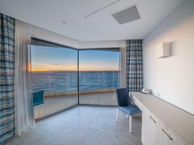 Modernes Zimmer mit großen Fenstern und Blick auf das Meer bei Sonnenuntergang.