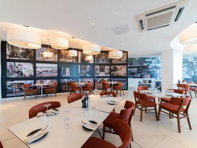 Modernes Restaurant mit stilvoller Einrichtung, roten Stühlen und großem Wandbild mit Reisefotos.