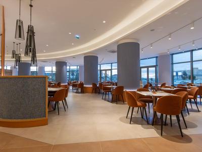 Modernes Restaurant mit braunen Stühlen und großen Fenstern mit Blick auf das Wasser.